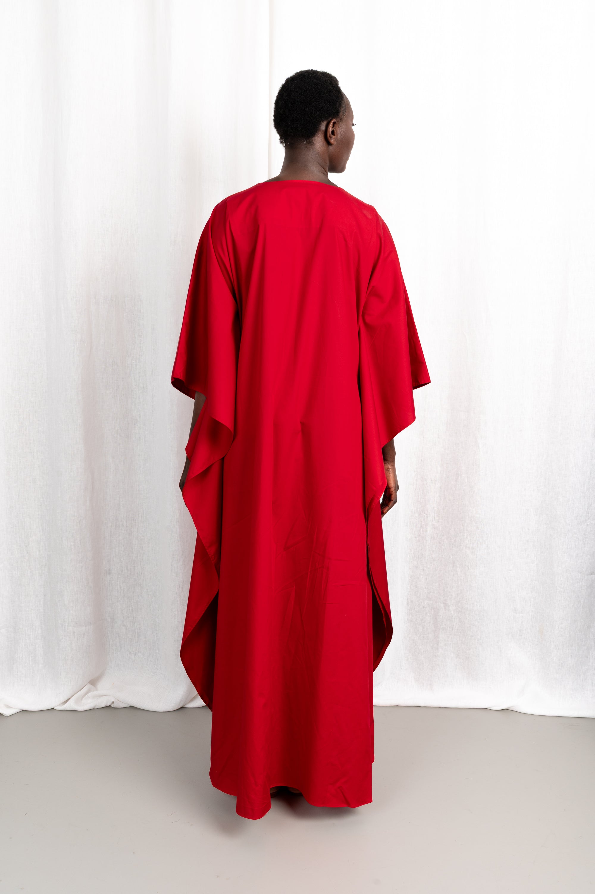 Modèle portant la robe Medina rouge col V en coton glacé, vue de dos #couleur_rouge profond