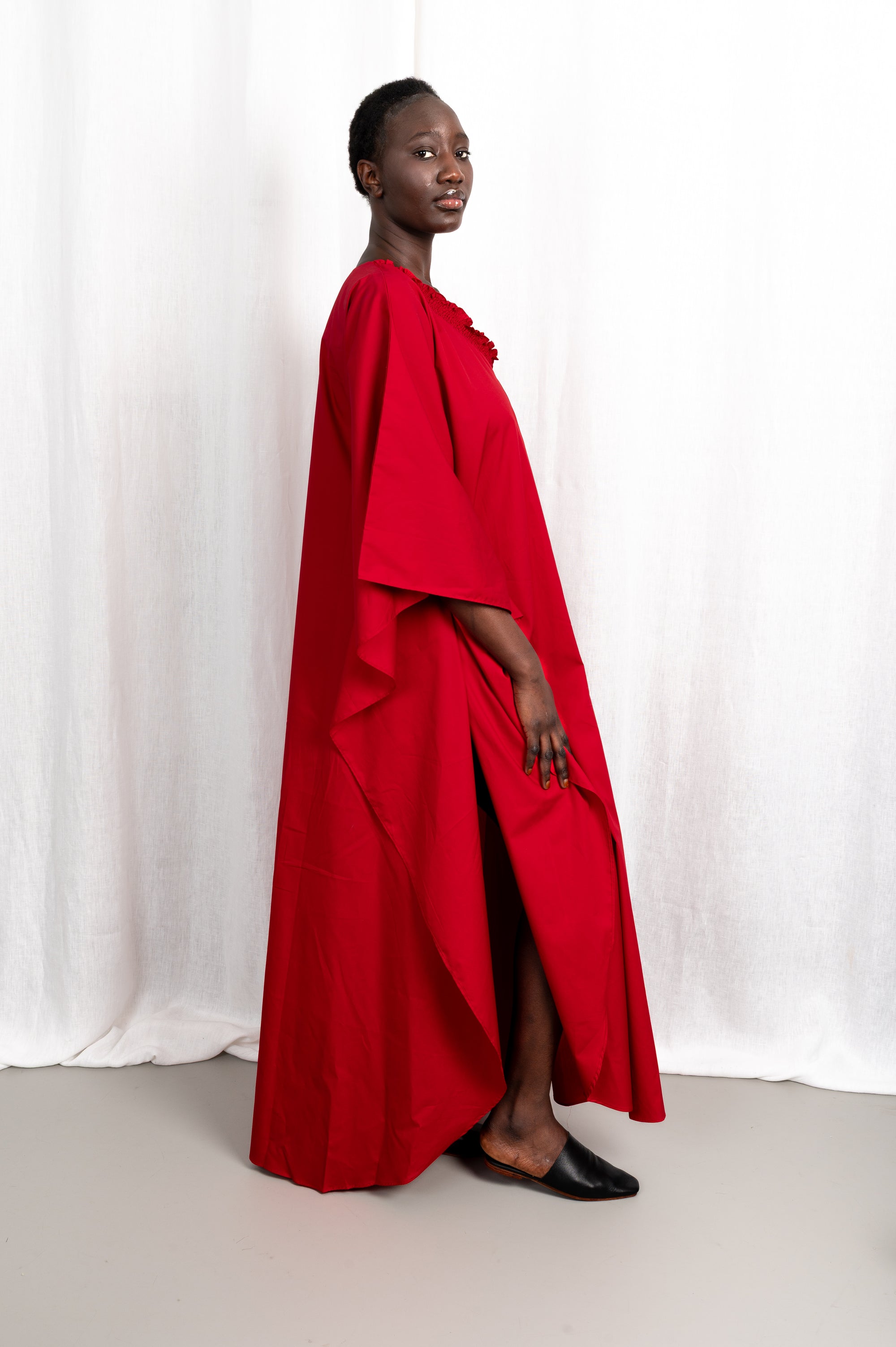 Modèle portant la robe Medina rouge col V en coton glacé, vue en mouvement #couleur_rouge profond