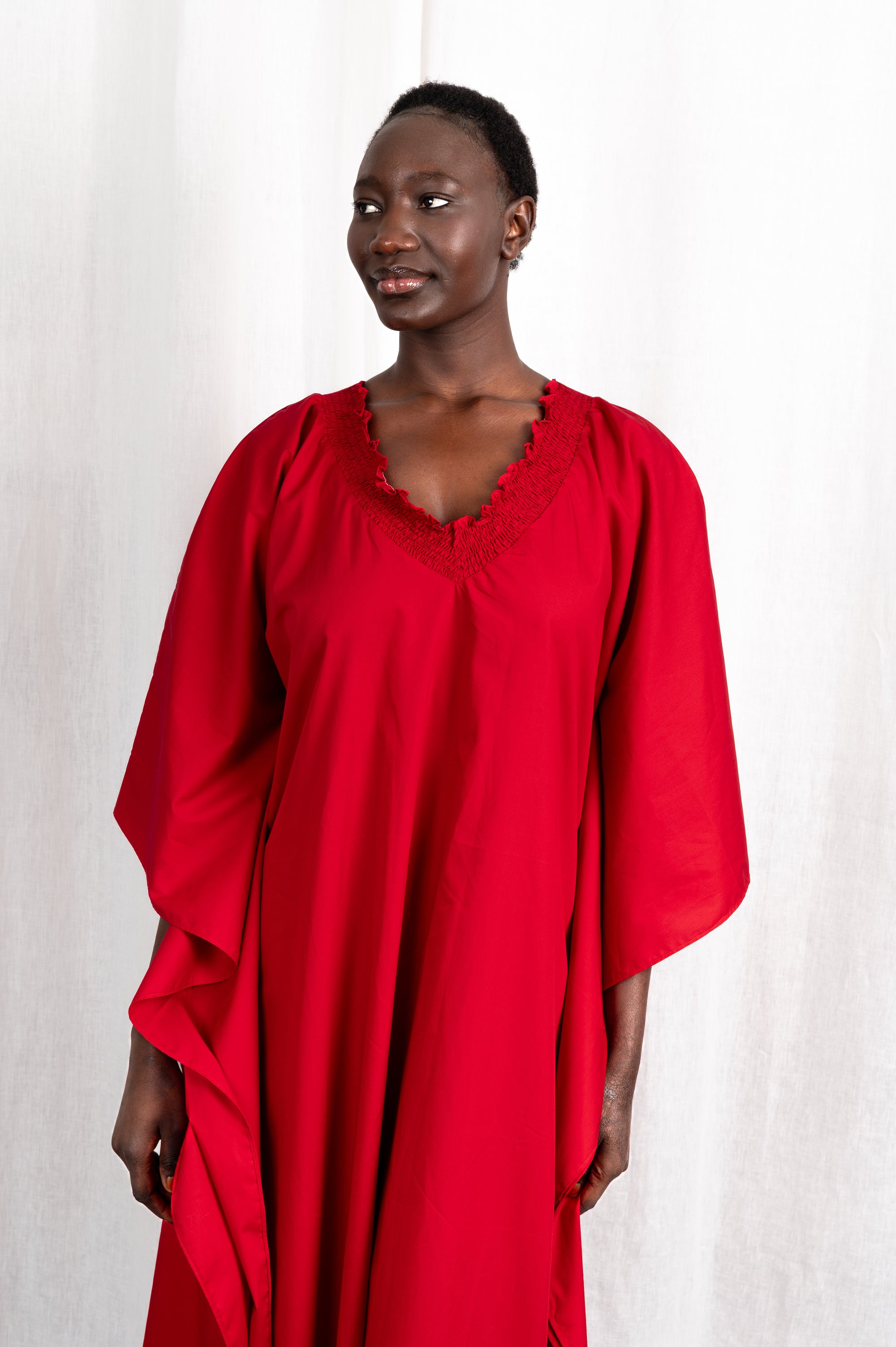 Modèle portant la robe Medina rouge col V en coton glacé, vue de portrait #couleur_rouge profond