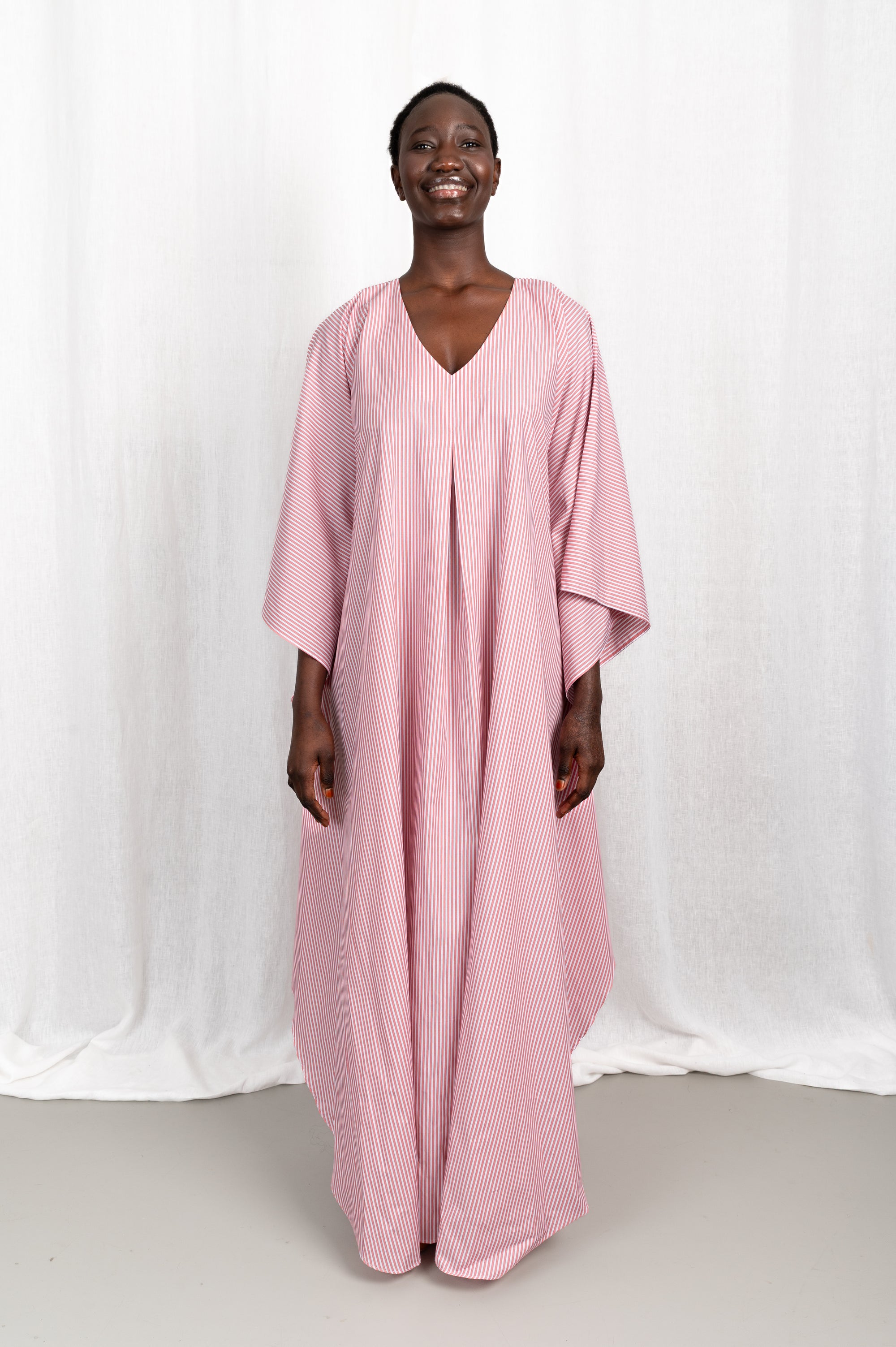 Modèle portant la robe Nia rose en coton et rayures roses, vue de face #couleur_rose