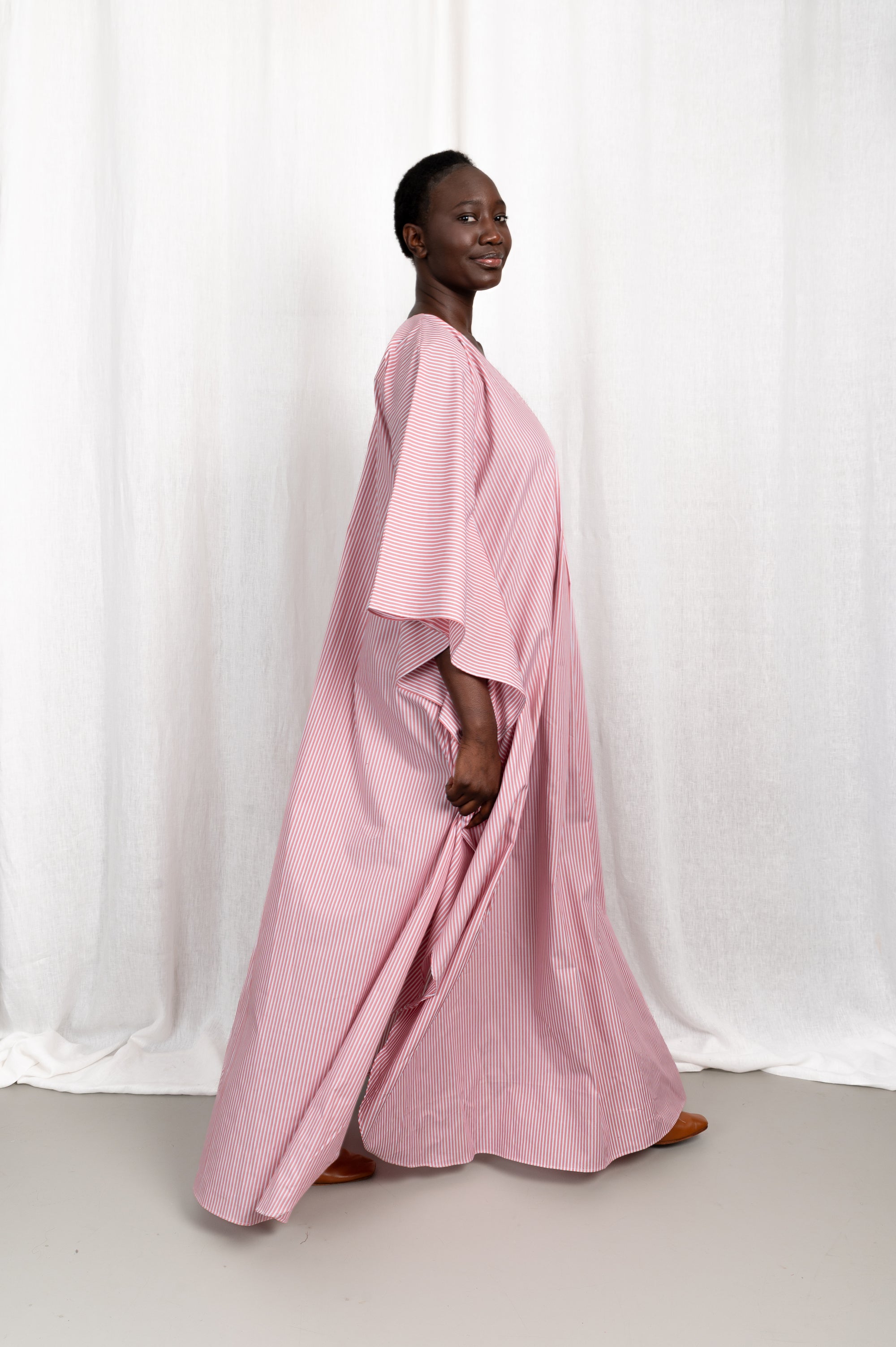 Modèle portant la robe Nia rose en coton et rayures roses, vue en mouvement #couleur_rose