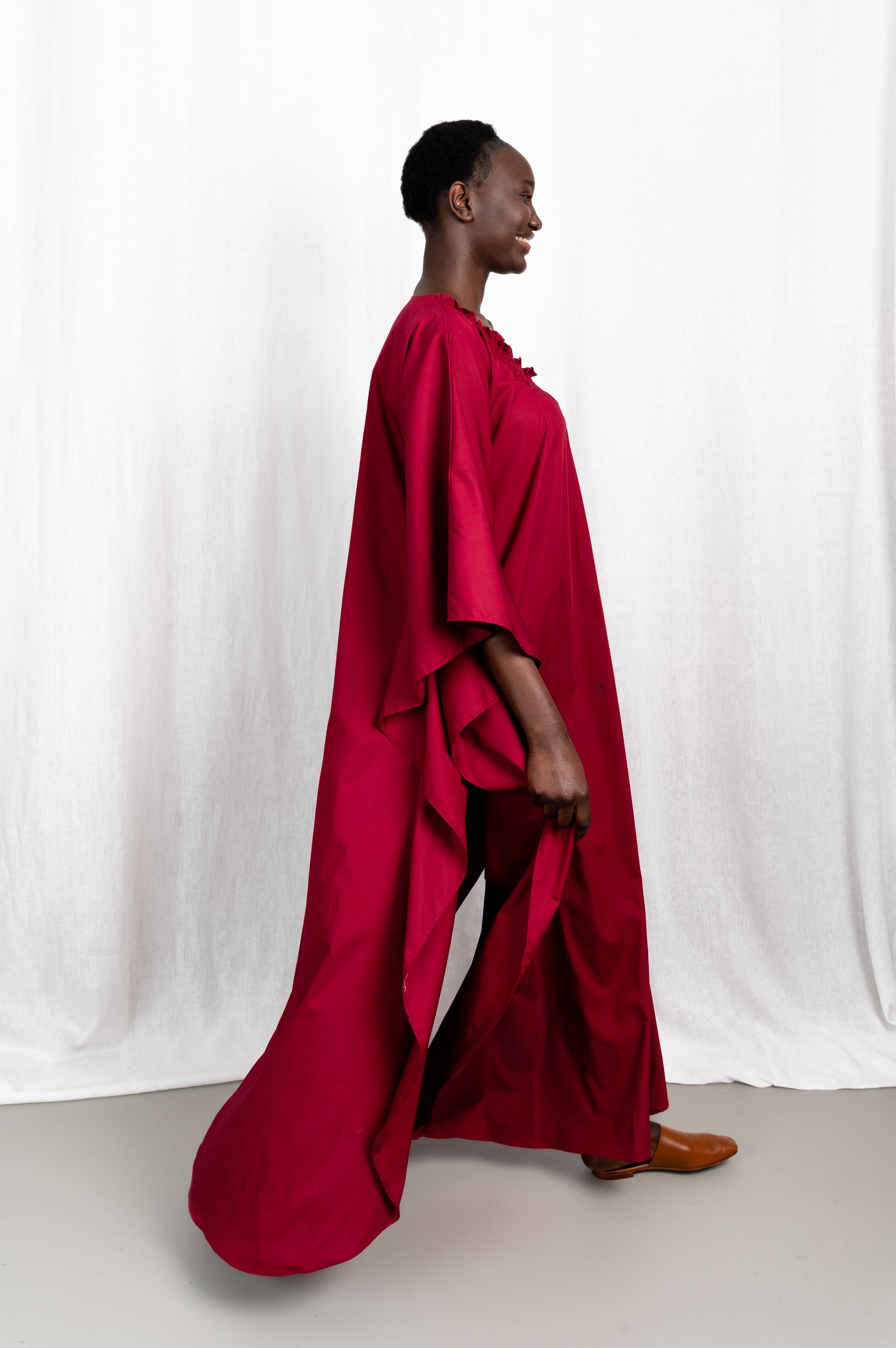 Modèle portant la robe Sira couleur cerise au col carré froncé, vue en mouvement #couleur_cerise