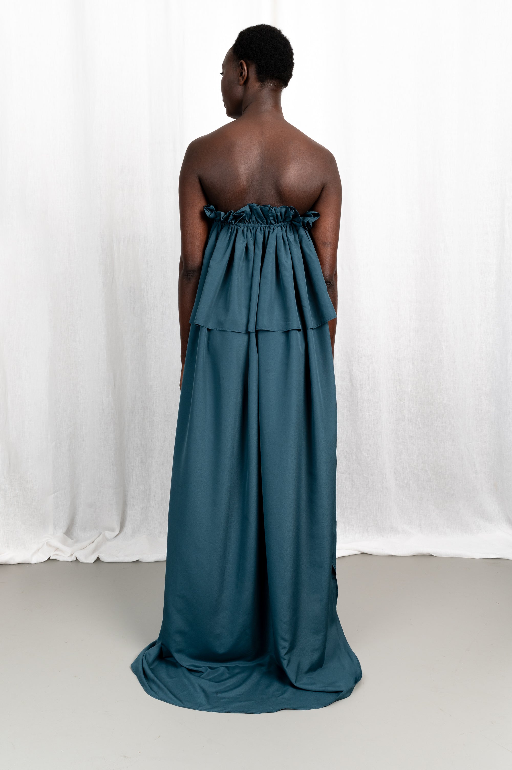 Modèle portant la robe Tamït en crêpe de Chine satiné, vue de dos #couleur_bleu vert profond