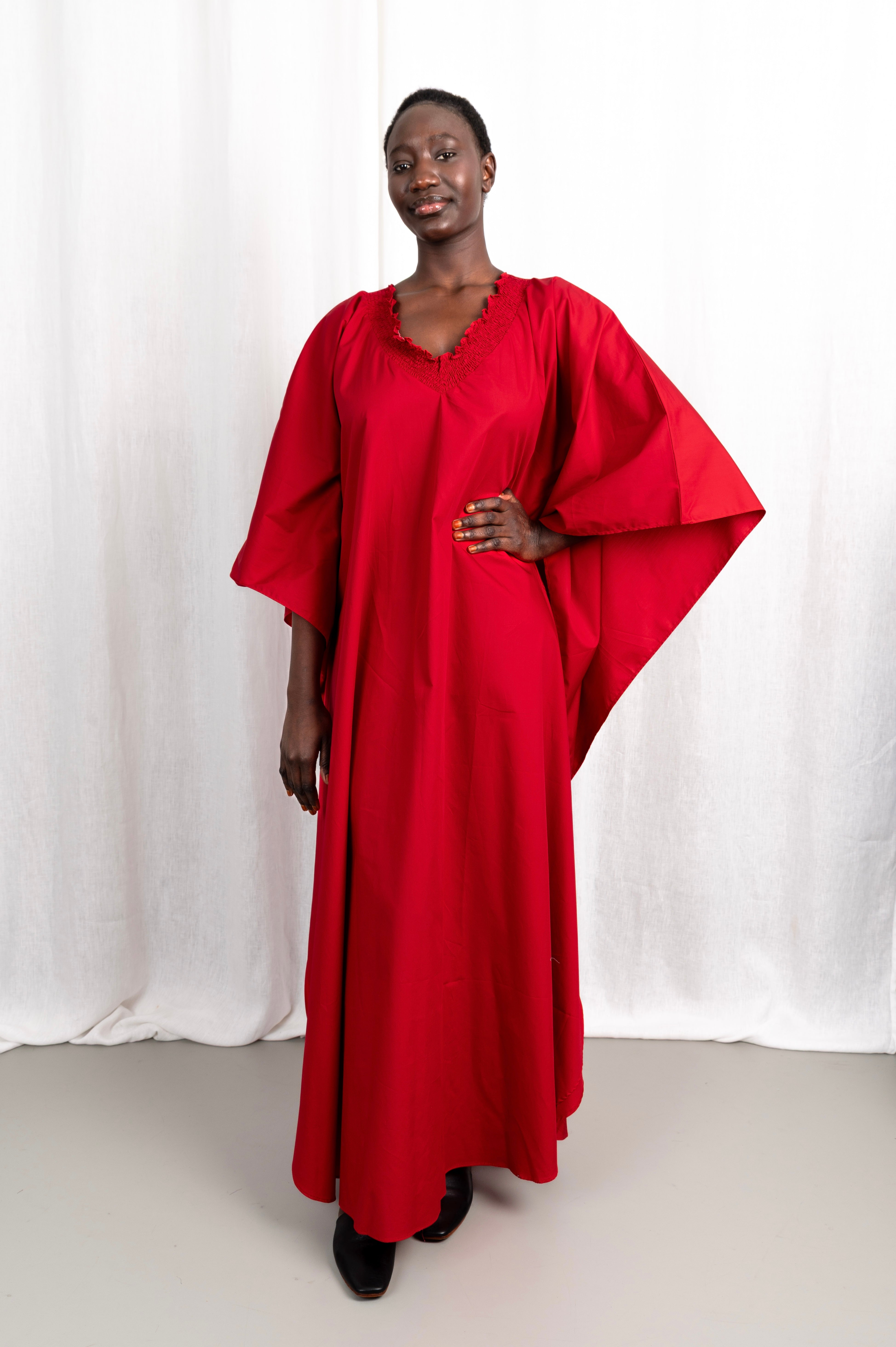 Modèle portant la robe Medina rouge col V en coton glacé, vue de face #couleur_rouge profond