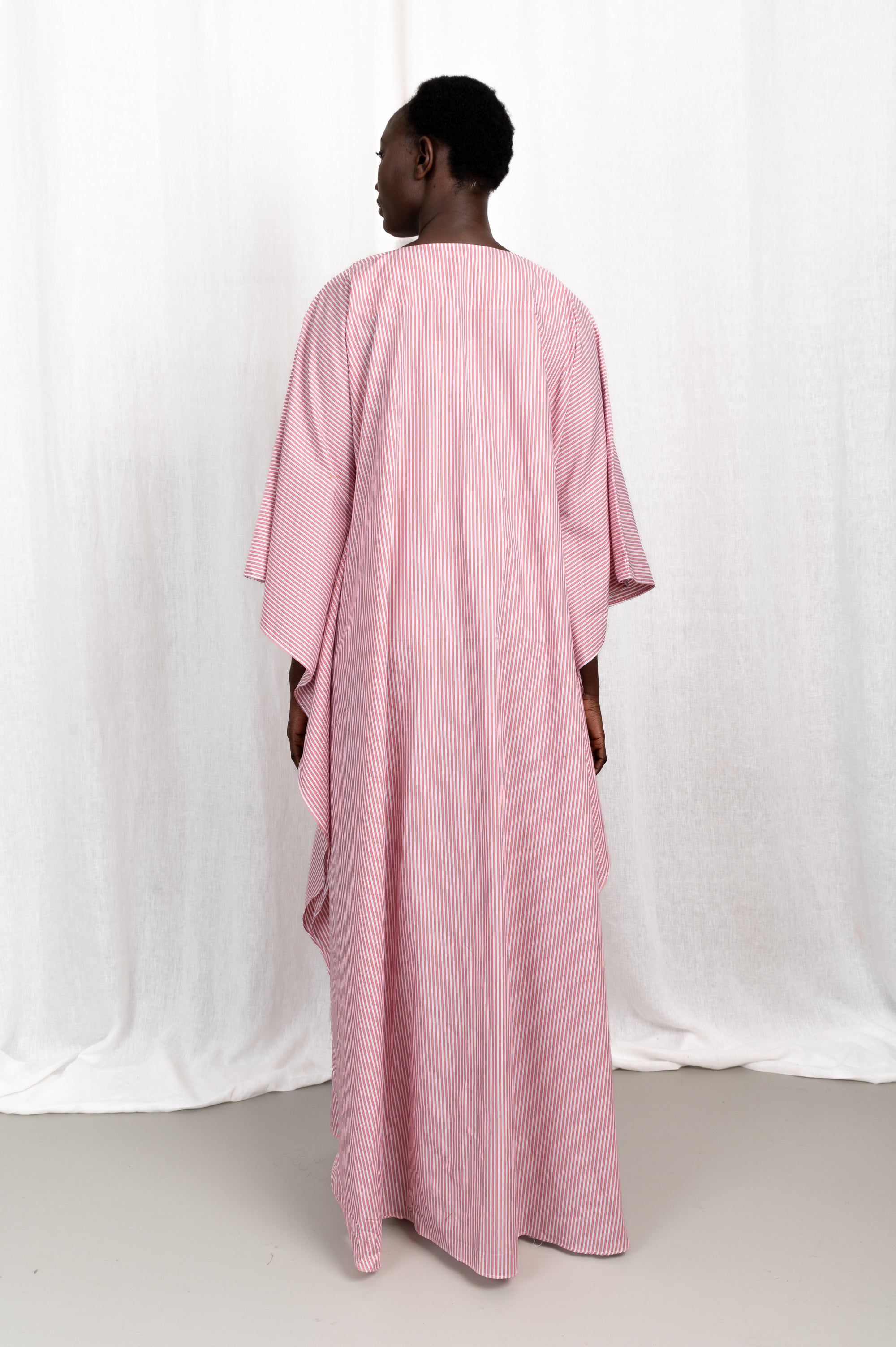 Modèle portant la robe Nia rose en coton et rayures roses, vue de dos #couleur_rose