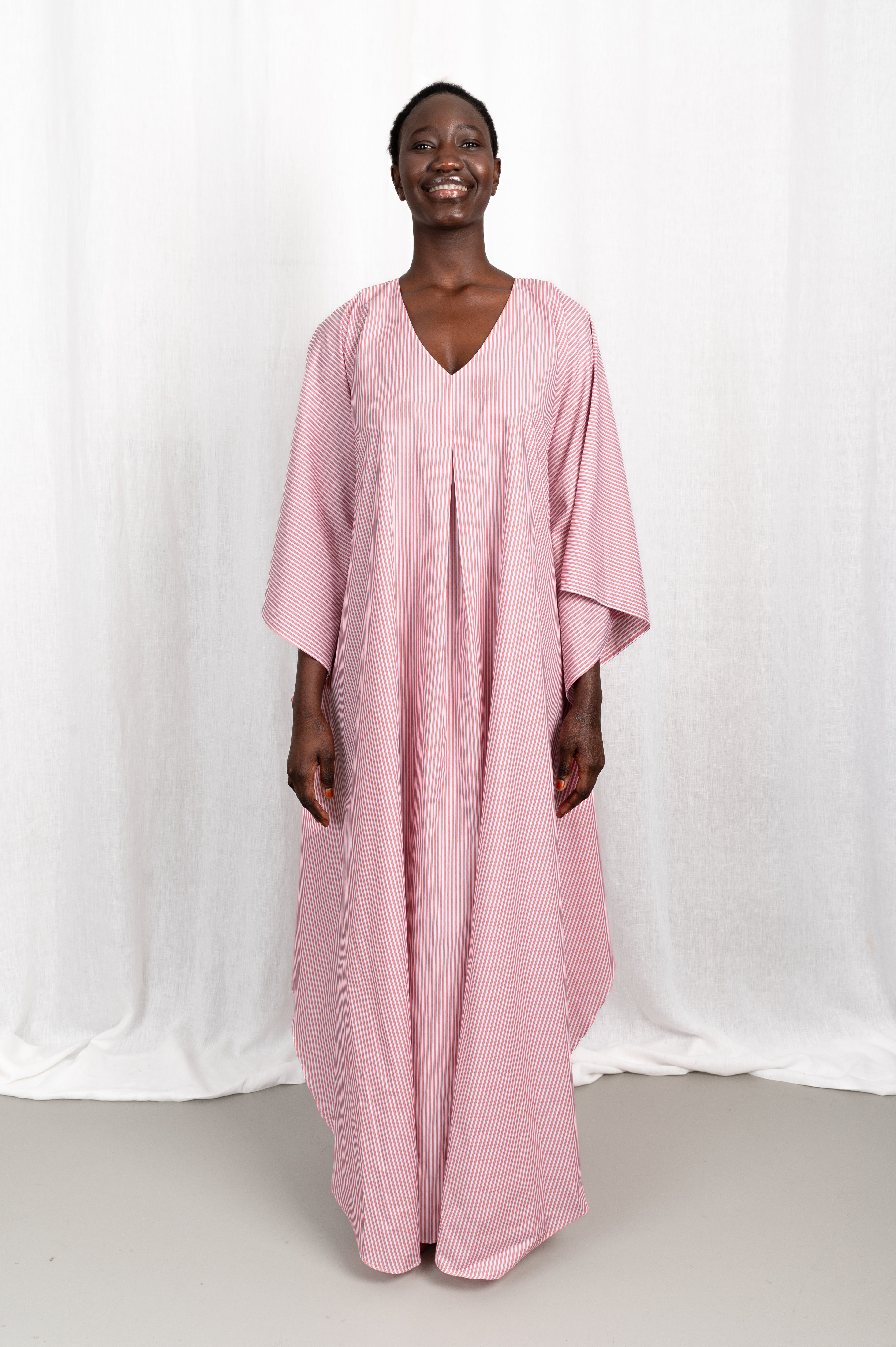 Modèle portant la robe Nia rose en coton et rayures roses, vue de face #couleur_rose