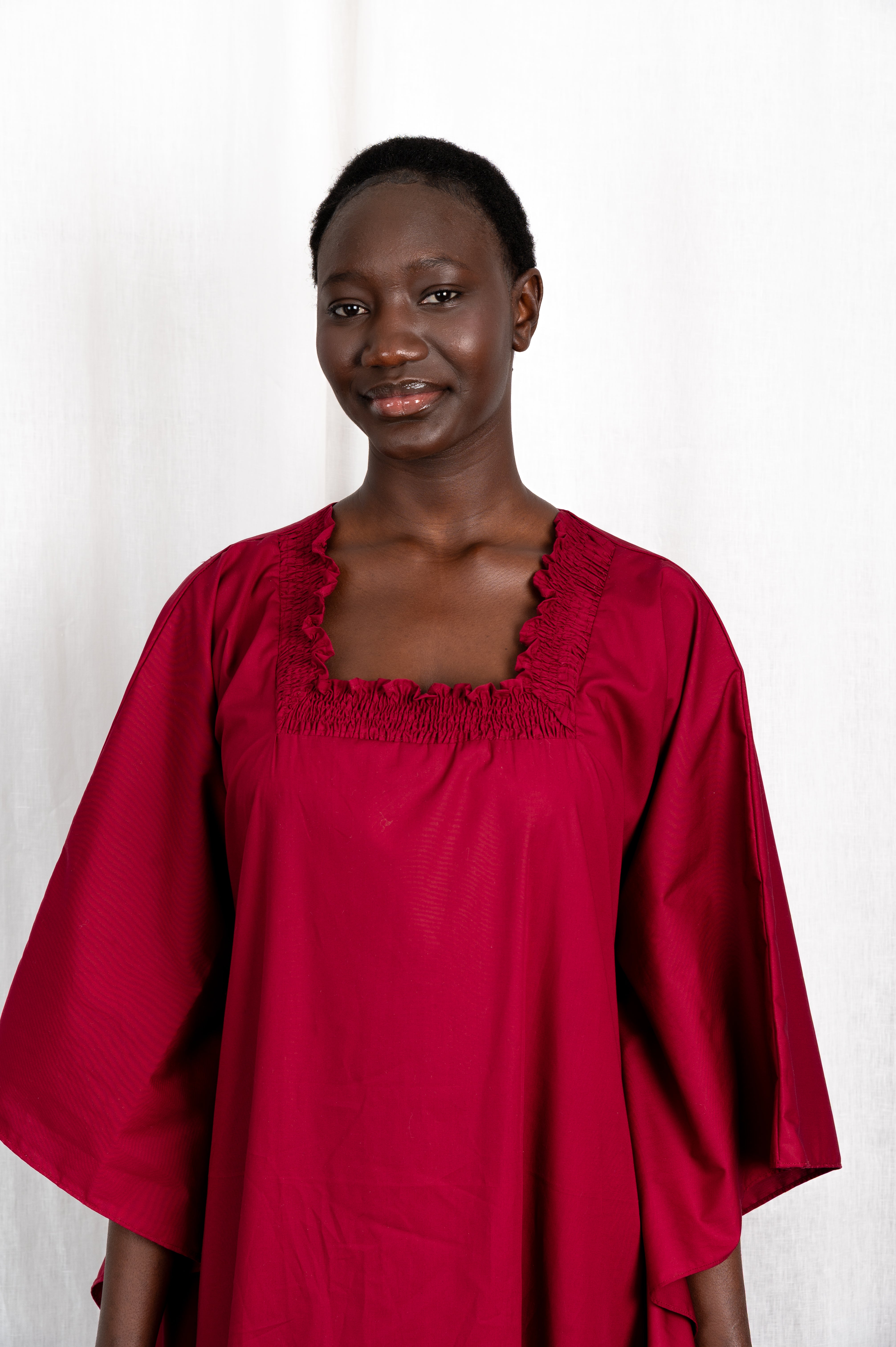 Modèle portant la robe Sira couleur cerise au col carré froncé, vue de portrait #couleur_cerise